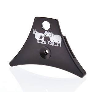 May include: Black metal dog whistle with a sheep design. The whistle has a round hole on the top and a smaller hole on the bottom.
