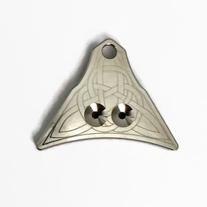May include: A silver whistle with a Celtic knot design and two holes. The whistle has a loop at the top for attaching to a lanyard.