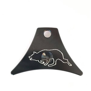 May include: Black metal dog whistle with a white silhouette of a running dog.