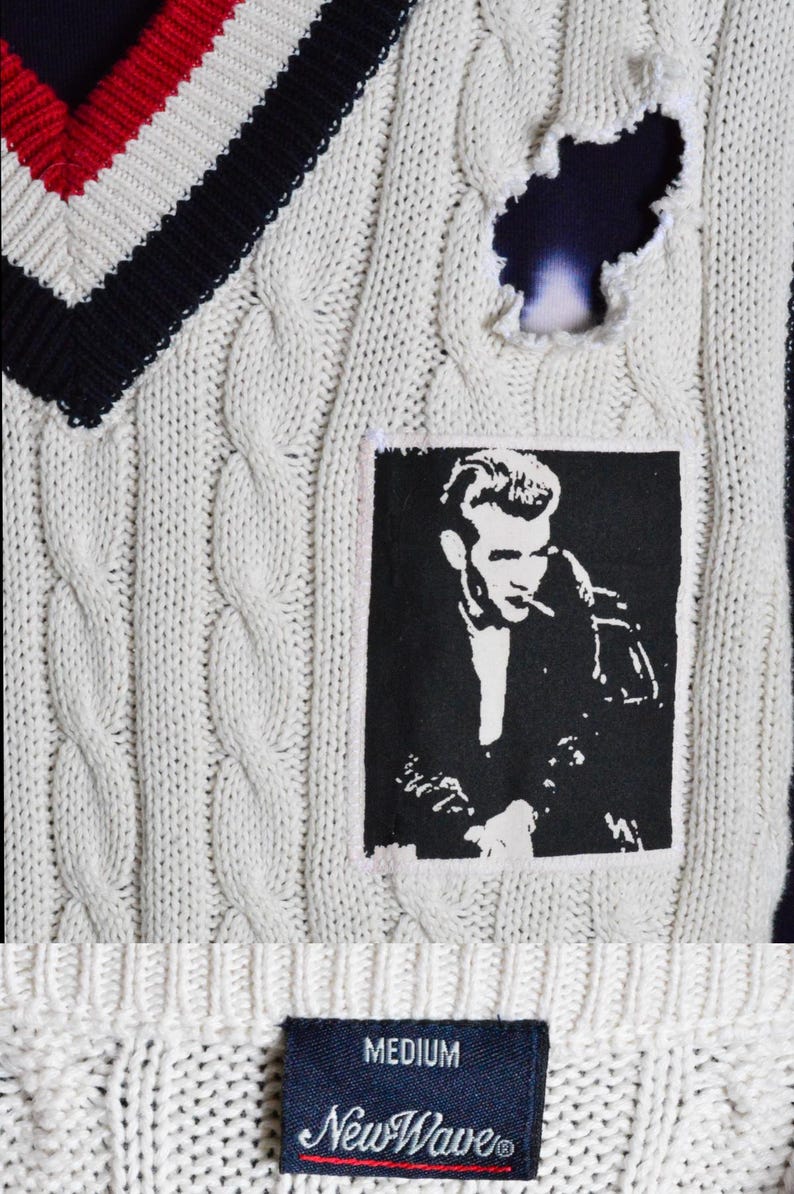 May include: Cream cable knit sweater vest with a V-neck featuring red, white, and navy blue stripes. A black and white graphic of a man smoking is on the front. The sweater has a distressed hole and a "MEDIUM" tag.