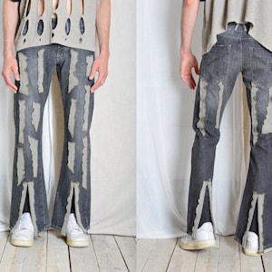 K&ouml;nnte beinhalten: Dunkelgraue Jeans mit vertikalen, hellgrauen, abgenutzten Akzenten. Die Jeans hat einen Schlitz am Beinabschluss und wird mit wei&szlig;en Turnschuhen getragen. Das Model tr&auml;gt ein hellgraues Oberteil mit Ausschnitten.