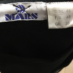 Puede incluir: Una etiqueta blanca con texto azul y un logotipo que dice "MAEN" con un bal&oacute;n de voleibol tachado. La etiqueta tambi&eacute;n tiene informaci&oacute;n de tama&ntilde;o: D/NL 48, F/B 48, GB 38.