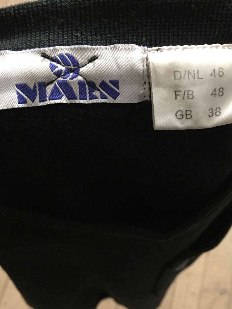 Puede incluir: Una etiqueta blanca con texto azul y un logotipo que dice "MAEN" con un bal&oacute;n de voleibol tachado. La etiqueta tambi&eacute;n tiene informaci&oacute;n de tama&ntilde;o: D/NL 48, F/B 48, GB 38.