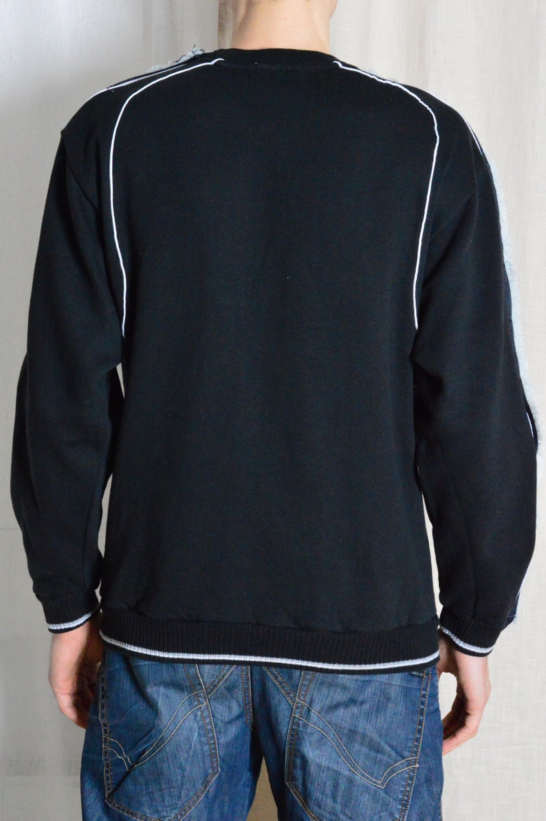 Puede incluir: Sudadera negra con ribetes blancos alrededor del cuello y las mangas. La sudadera tiene un dobladillo y pu&ntilde;os de canal&eacute;.