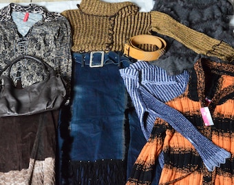 Op de afbeelding: Een verzameling kledingstukken, waaronder een bruin en zwart gestreepte trui, een bruin en zwart luipaardprint trui, een blauwe denim rok met franjes, een bruine suède rok, een bruine leren tas, een blauw en wit gestreepte trui en een oranje en zwart gestreepte trui.
