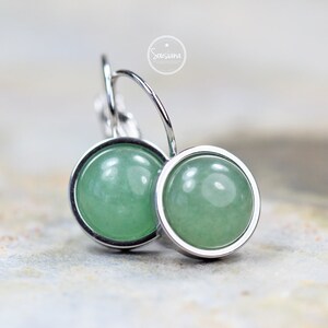 Peut inclure: Une paire de boucles d'oreilles cr&eacute;oles en argent avec des cabochons de pierres pr&eacute;cieuses vertes. Les boucles d'oreilles sont simples et &eacute;l&eacute;gantes.