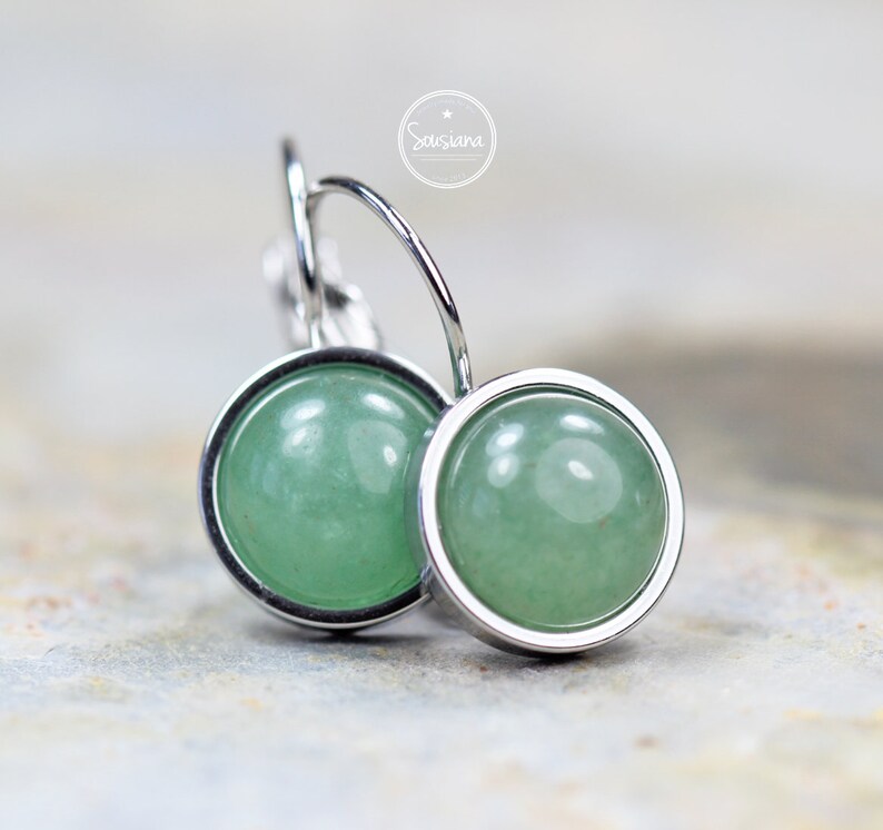 Peut inclure: Une paire de boucles d'oreilles cr&eacute;oles en argent avec des cabochons de pierres pr&eacute;cieuses vertes. Les boucles d'oreilles sont simples et &eacute;l&eacute;gantes.