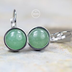 Peut inclure: Une paire de boucles d'oreilles en argent avec des cabochons de pierres pr&eacute;cieuses vertes. Les boucles d'oreilles ont un design simple et &eacute;l&eacute;gant et sont parfaites pour tous les jours.