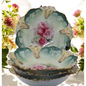 May include: Set of four vintage porcelain bowls with a green and white floral design. The bowls have a scalloped edge and are decorated with pink and red flowers.