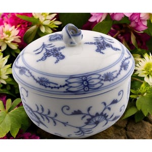 May include: A white porcelain sugar bowl with a blue and white floral design. The lid has a rosebud finial.