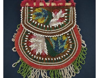 May include: A brown beaded pouch with a red velvet trim and a green and white beaded fringe. The pouch features floral designs in white, yellow, blue, and red beads. The top of the pouch has a red fabric trim.