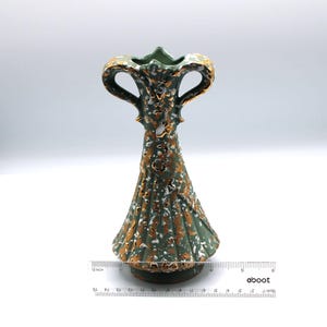 May include: A green ceramic vase with gold accents and two handles. The vase has a textured surface and a white glaze. It is approximately 6 inches tall.