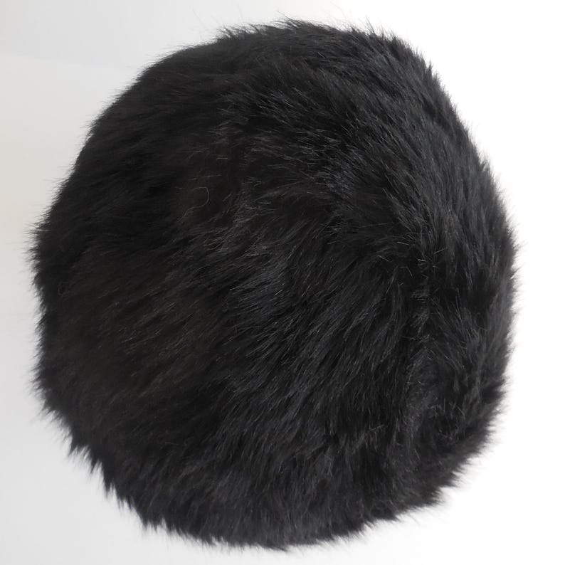 May include: A round, black fur hat. The hat is made of soft, dark fur and has a rounded shape. The hat is a solid black colour and appears to be a winter accessory.