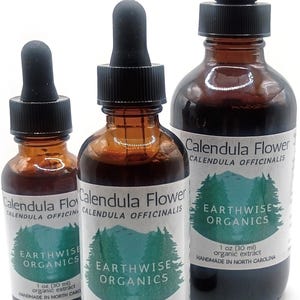 May include: Three amber glass dropper bottles containing Calendula Flower organic extract. Labels feature a green forest graphic, the text Earthwise Organics, and volume measurements of 1 oz (30 ml) and 2 oz (60 ml) printed on the front.