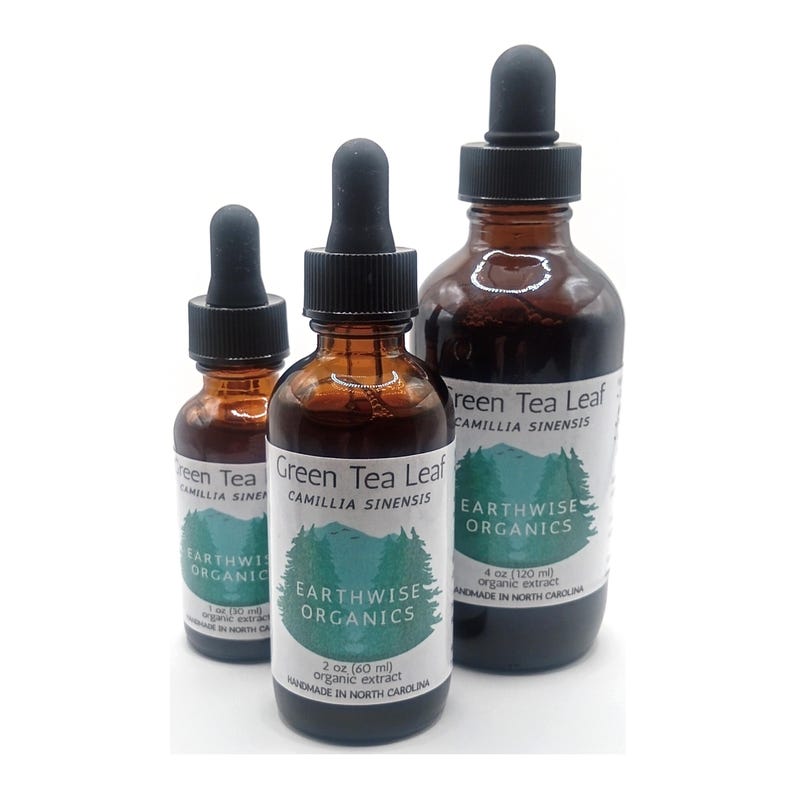 May include: Three amber glass bottles with black droppers, labeled "Green Tea Leaf" and "Earthwise Organics." The bottles contain organic extract, with sizes of 1 oz, 2 oz, and 4 oz. The labels also state "Handmade in North Carolina."
