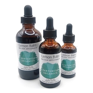 May include: Three amber glass bottles of Lemon Balm extract with black droppers. Each bottle has a white label with the text "Lemon Balm", "Melissa Officinalis", and "Earthwise Organics". The bottles are labeled with 1 oz (30 ml), 2 oz (60 ml), and 4 oz (120 ml).