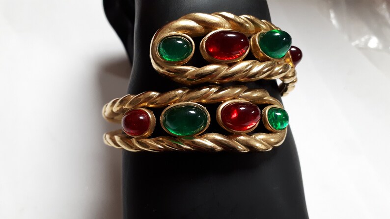Puede incluir: Dos pulseras de tono dorado con un dise&ntilde;o de cuerda y piedras ovaladas rojas y verdes.