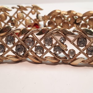 May include: A gold-tone bracelet with a delicate, interwoven design featuring clear rhinestones.