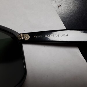 May include: Close-up of the black Ray-Ban sunglasses frame with the text "Ray-Ban U.S.A." on the side.