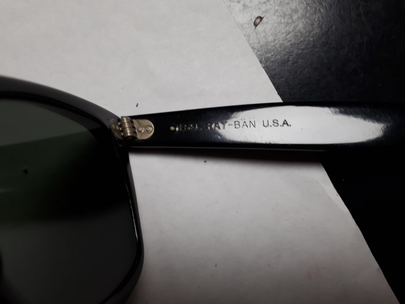May include: Close-up of the black Ray-Ban sunglasses frame with the text "Ray-Ban U.S.A." on the side.