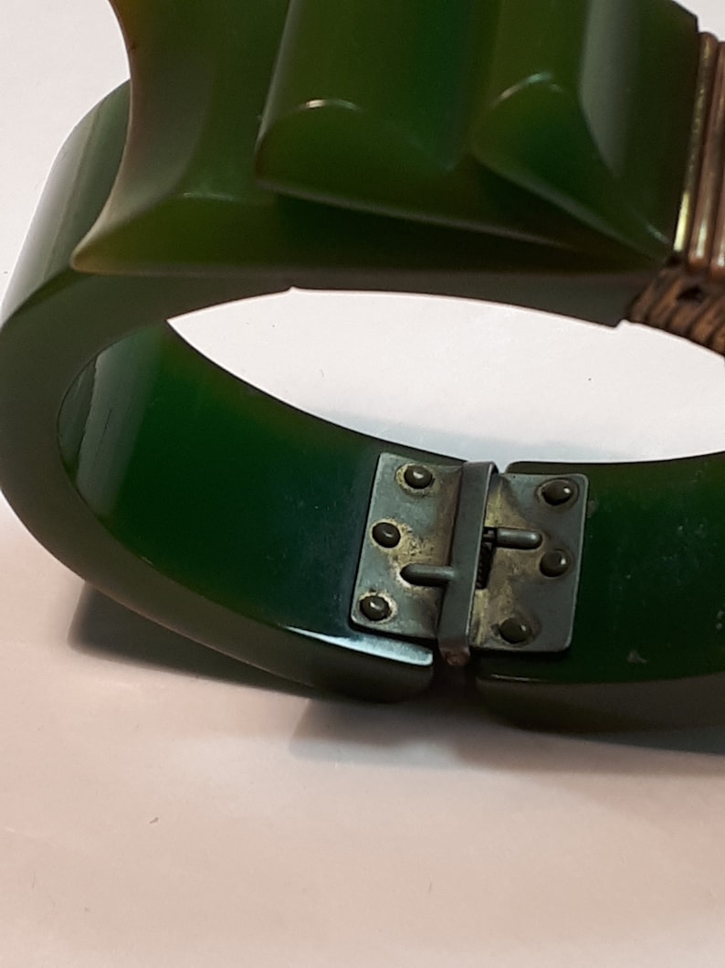 May include: A green plastic bangle bracelet with a metal clasp. The bracelet is made of two pieces that snap together.