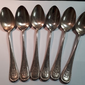 Puede incluir: Juego de seis cucharaditas de plata con un monograma grabado. Las cucharas tienen un diseño clásico y están en excelente estado.
