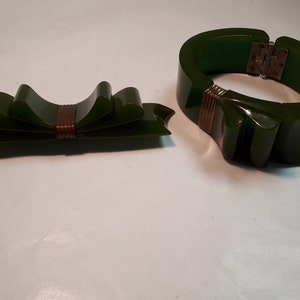 May include: A set of two green vintage bakelite jewelry pieces. A bow-shaped brooch with a brown center and a wide bangle bracelet with a gold-toned accent.
