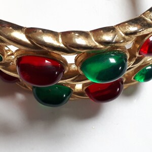 Puede incluir: Pulsera de tono dorado con piedras cabuj&oacute;n rojas y verdes.