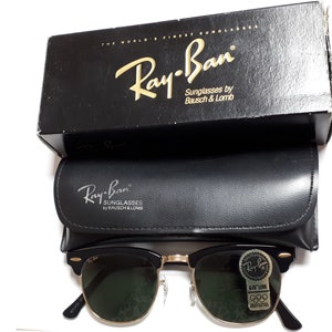 May include: Black Ray-Ban sunglasses with gold-tone accents, green lenses, and a black leather case. The sunglasses are displayed with their original black box, which reads "THE WORLD'S FINEST SUNGLASSES".