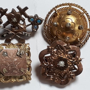 May include: Four antique gold brooches with pearl and opal accents. The brooches feature intricate designs including a heart, anchor, cross, and floral motifs.