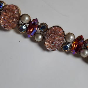 Könnte beinhalten: Ein Vintage-Armband mit pinkfarbenen, roten und blauen, schillernden Glassteinen und weißen Perlen.