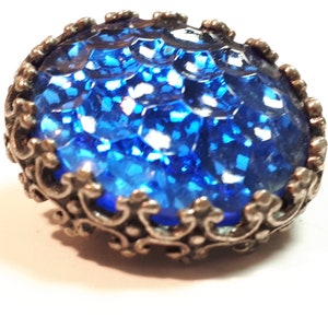 May include: A blue glass button with a silver filigree design around the edge.