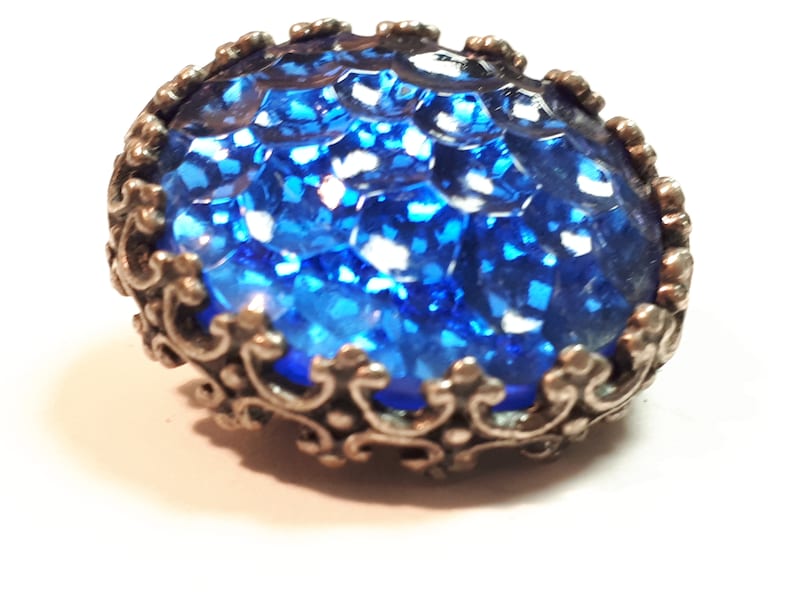 May include: A blue glass button with a silver filigree design around the edge.