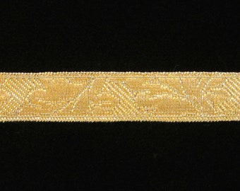 May include: A close-up of a gold trim with a geometric pattern. The trim is woven and has a subtle sheen.