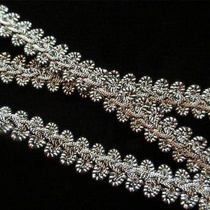 May include: Two silver trim pieces with a scalloped edge. The trim is made of small, tightly woven loops.