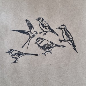 Five hand printed images of the rubber lino stamps on brown kraft paper, birds included are the Swallow, Goldfinch, Grey Wagtail, Blue Tit and a Woodpecker.