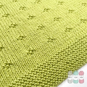 May include: Close-up of a knitted fabric in a bright green color. The fabric has a textured pattern with small raised dots. The fabric is shown next to three balls of yarn in different colors: gray, teal, and pink.