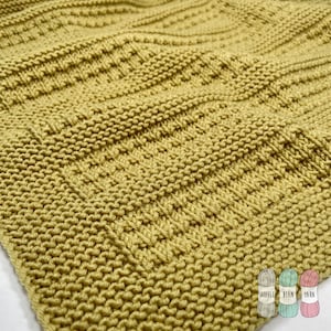 May include: A close-up of a knitted fabric in a mustard yellow color. The fabric has a textured pattern with raised lines and a subtle sheen.