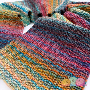 May include: A multi-coloured, hand-knitted scarf with a striped design. The scarf displays a mix of bright colours, including blue, orange, red, and green. The knitted texture is visible, highlighting the craftsmanship. The scarf is folded and presented.