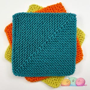 May include: Three knitted squares in teal, orange, and yellow. The teal square is central, with the orange and yellow squares peeking out. The knitted texture is prominent, with each stitch clearly defined. The squares are likely handmade.
