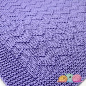 May include: A close-up of a purple knitted fabric with a diamond pattern.