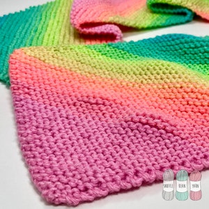 May include: A hand-knitted scarf in a vibrant rainbow gradient of pink, orange, yellow, green, and teal. The scarf is made of soft yarn and features a textured knit stitch. The Snuffle Bean Yarn logo is in the bottom right corner.