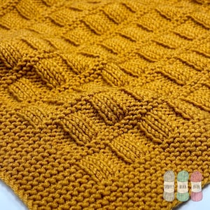 May include: Close-up of a knitted fabric in a deep mustard yellow color. The fabric has a textured, ribbed pattern.