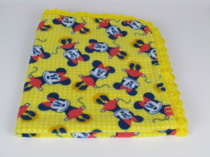 Pu&ograve; includere: Coperta per neonati in pile giallo con stampa di Topolino e bordo all'uncinetto giallo.
