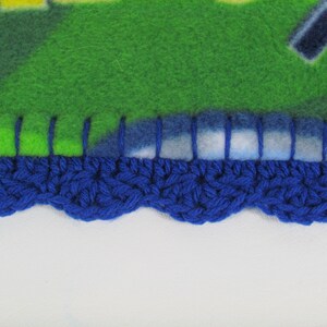 May include: A blue crocheted border with a scalloped edge is sewn to a green and blue fleece blanket.