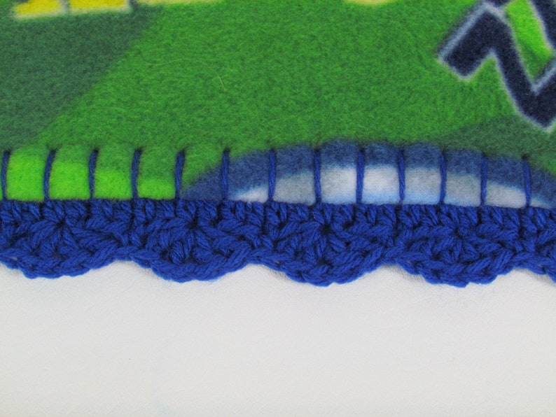 May include: A blue crocheted border with a scalloped edge is sewn to a green and blue fleece blanket.