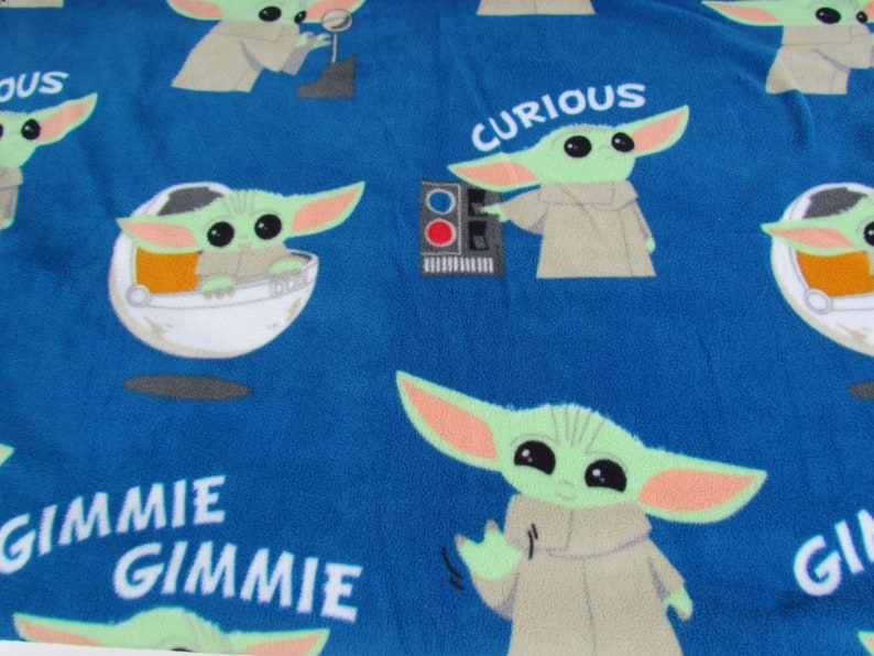 May include: Blue fabric with a repeating pattern of a green alien character with large eyes. The alien is wearing a brown robe and is in different poses. The fabric also has the words "Curious", "Gimme", and "Gimme" printed on it.