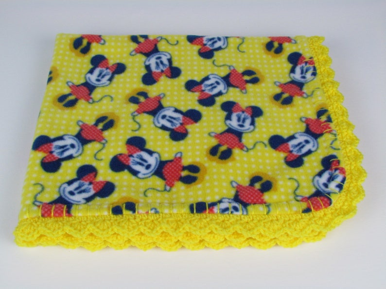Pu&ograve; includere: Coperta per neonati in pile giallo con stampa Mickey Mouse e bordo all'uncinetto giallo.