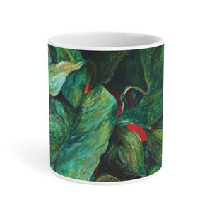 Peut inclure: Une tasse en céramique blanche avec un motif abstrait vert et rouge. Le motif présente des motifs tourbillonnants de feuilles vertes avec des touches de rouge.