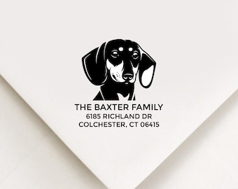May include: White envelope with a black and white illustration of a dachshund dog. The text "THE BAXTER FAMILY" is above the address: 6185 RICHLAND DR, COLCHESTER, CT 06415.